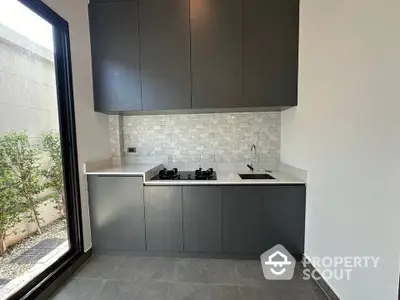 Modern kitchen with sleek cabinetry and gas stove, featuring a minimalist design and natural light.