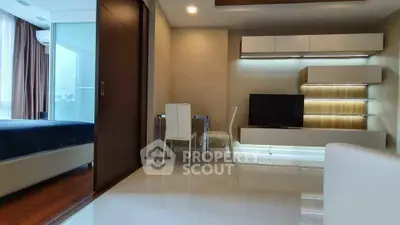 Modern living room with sleek furniture and open layout adjacent to a cozy bedroom.