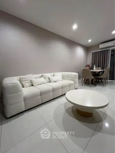 Modern living room with plush white sofa and sleek round coffee table, perfect for stylish relaxation.