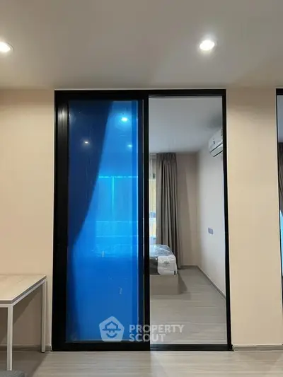 Modern bedroom with sliding glass door and air conditioning, featuring sleek design and natural light.