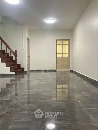 Spacious interior with marble flooring and wooden staircase, ideal for modern living.