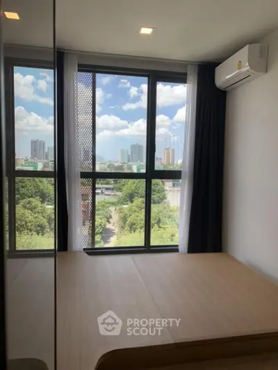 Modern bedroom with large windows offering a stunning city view, featuring sleek design and natural light.