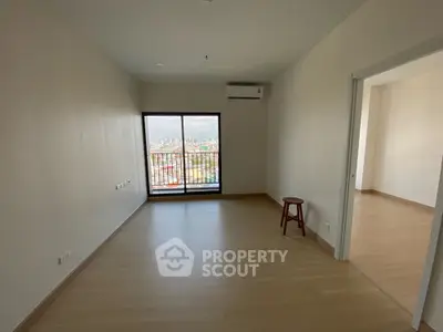 Spacious empty room with wooden flooring and large window offering city view