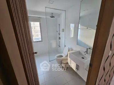 Modern bathroom with glass shower and sleek fixtures in a bright apartment.