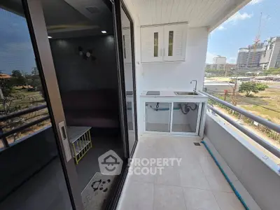 Modern balcony with sleek design and city view, featuring a small kitchenette and sliding glass doors.