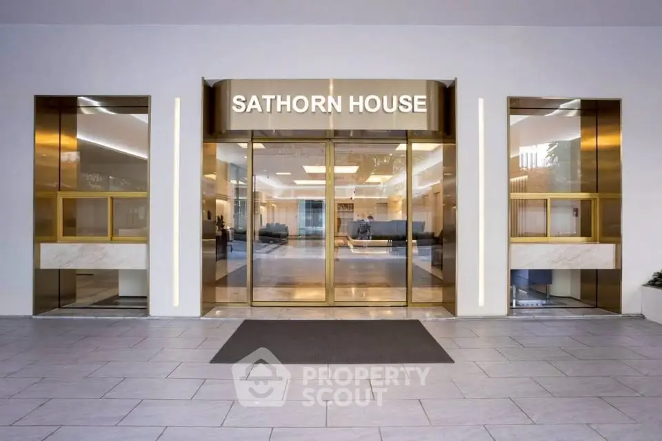 Elegant entrance of Sathorn House with modern glass doors and sleek design.
