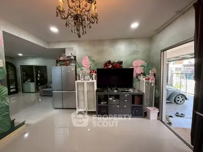 Spacious living room with modern decor and open layout, featuring elegant chandelier and large TV unit.