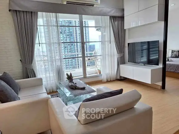 Modern living room with large windows and city view, featuring sleek furniture and stylish decor.