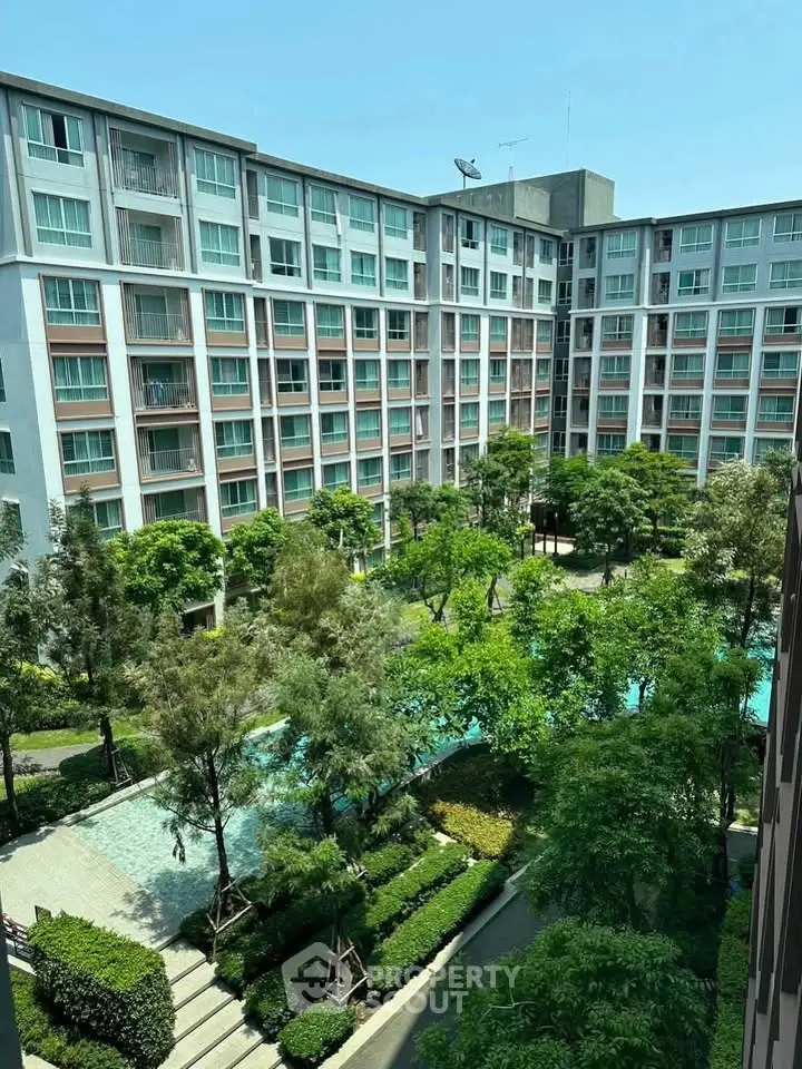 Modern apartment complex with lush green courtyard and pool view