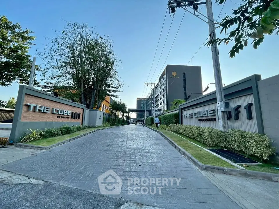 Modern residential building entrance with landscaped greenery and clear signage.