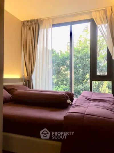 Cozy bedroom with large window and lush green view, perfect for relaxation.