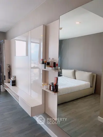 Modern bedroom with sleek design and large mirror reflecting natural light.