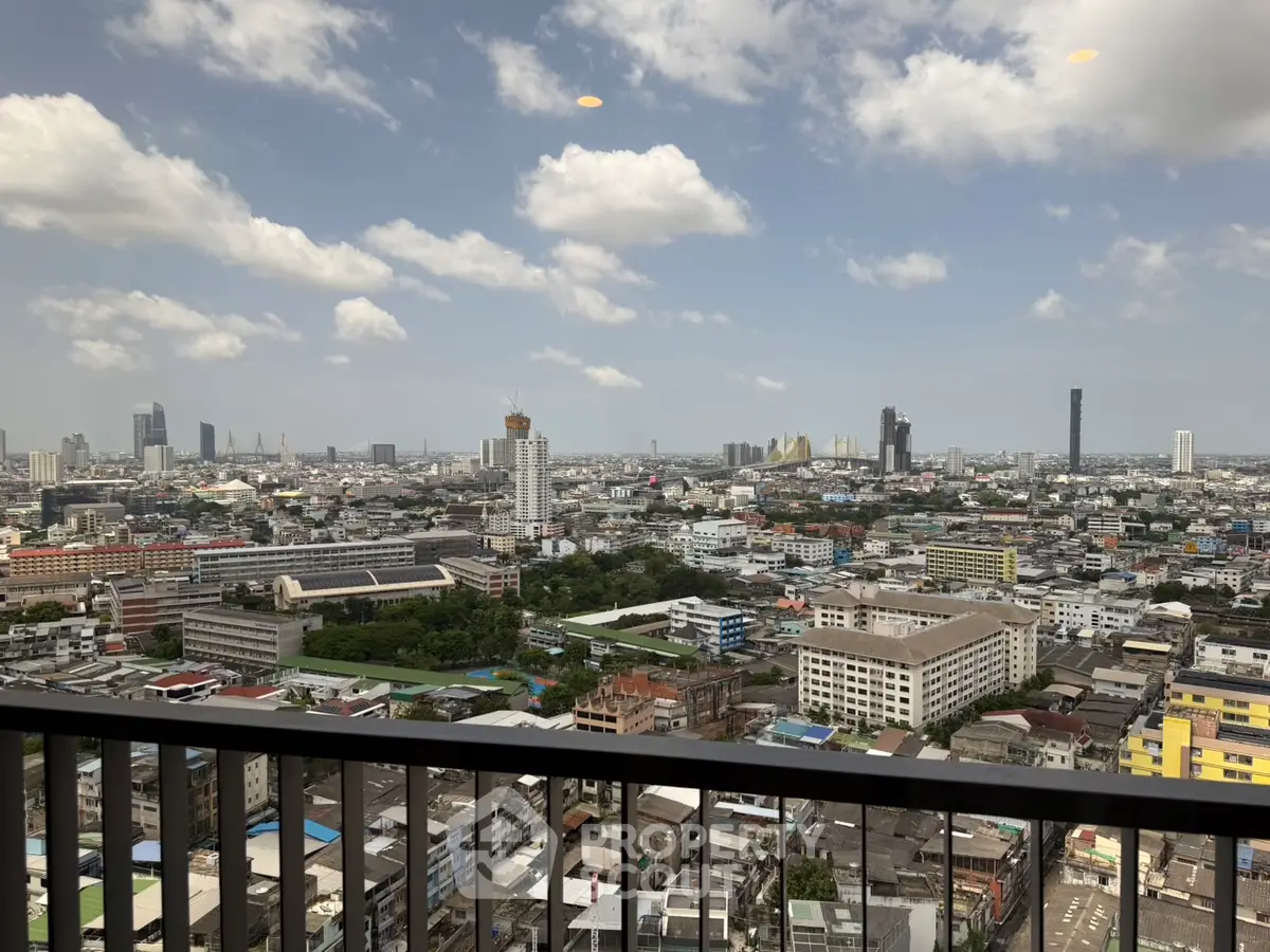 Stunning cityscape view from a high-rise balcony showcasing urban skyline under a clear blue sky.