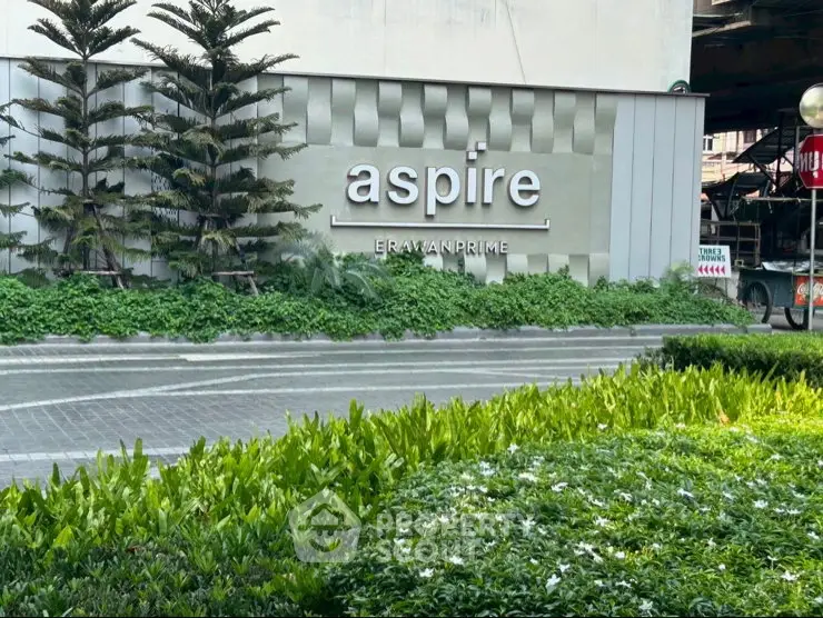 Modern building entrance with lush greenery and stylish signage at Aspire Erawan Prime.