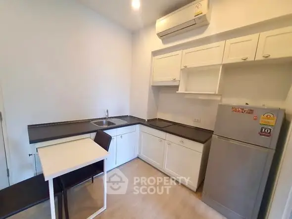 Modern kitchen with sleek cabinets and compact dining area in a cozy apartment.