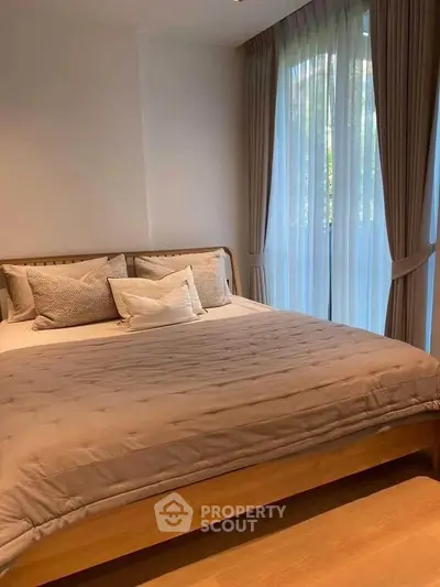 Cozy bedroom with large windows and elegant curtains, perfect for relaxation and comfort.