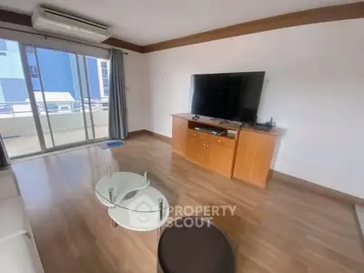 Spacious living room with modern TV setup and balcony access