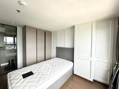 Modern bedroom with minimalist design and city view, featuring a single bed and built-in wardrobe.