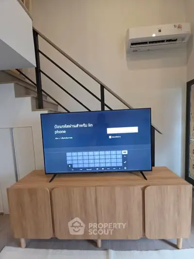 Modern living room with stylish TV setup and air conditioning unit.