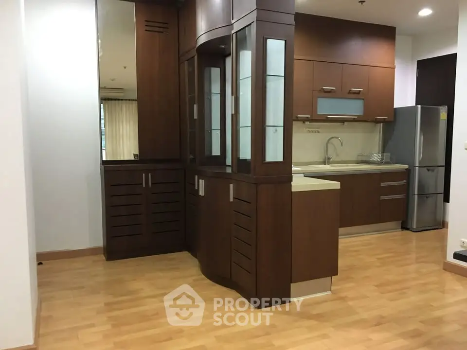 Modern kitchen with wooden cabinetry and stainless steel appliances in a spacious apartment.