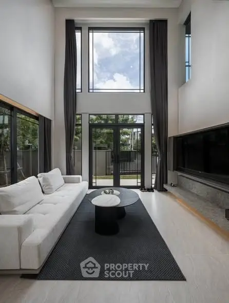 Luxurious double-height living room with floor-to-ceiling windows and modern decor.