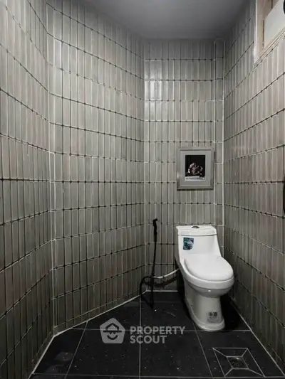 Modern bathroom with sleek tiled walls and contemporary toilet design.