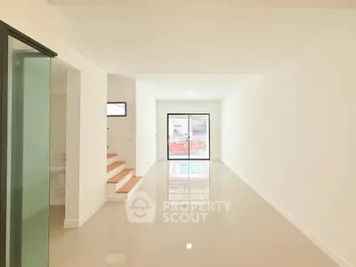 Spacious modern living room with glossy tiled floors and large window for natural light.