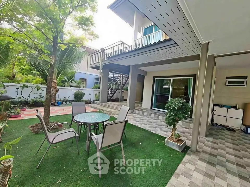 Charming outdoor garden area with patio furniture and lush greenery, perfect for relaxation and entertaining.