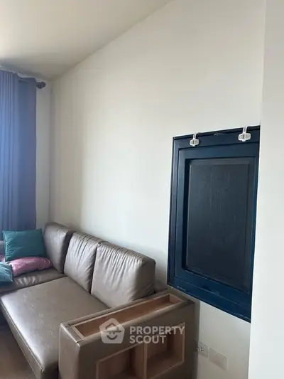 Modern living room with sleek leather sofa and large window, offering a cozy and stylish ambiance.