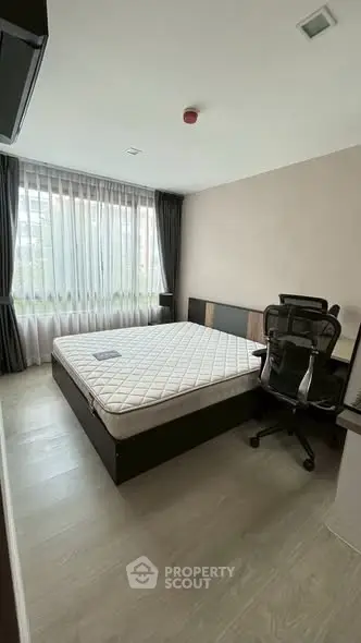 Modern bedroom with large window and office chair, perfect for comfort and productivity.