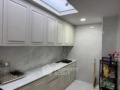 Modern kitchen with sleek cabinetry and gas stove under skylight
