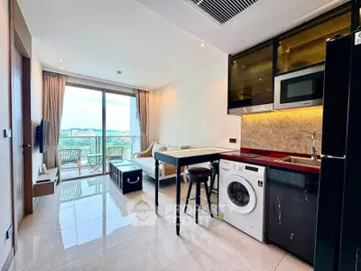 Modern open-plan living room with kitchen, featuring a washing machine and balcony with scenic view.