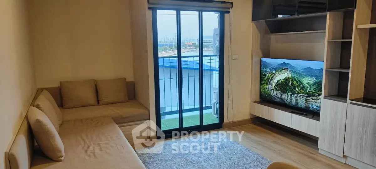 Modern living room with cozy seating and large TV, featuring a balcony view.