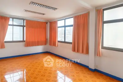Spacious empty room with vibrant orange tiled flooring and large windows.