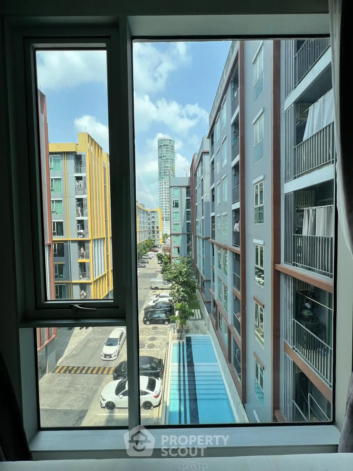 Modern urban apartment view with pool and parking, showcasing vibrant city living.
