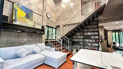 Modern loft-style living room with high ceilings and industrial staircase