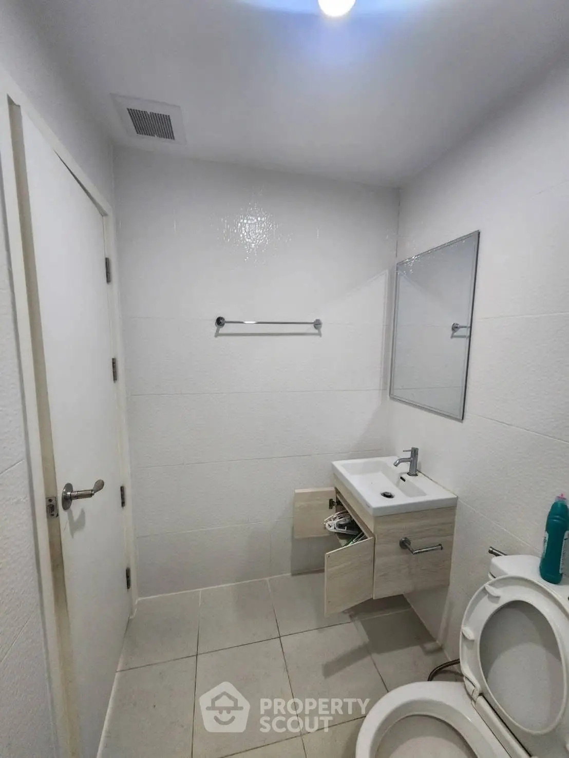 Modern bathroom with sleek fixtures and minimalist design, featuring a compact vanity and toilet.