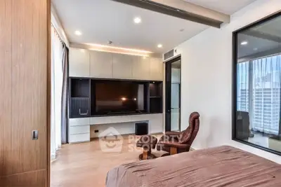 Modern bedroom with sleek built-in entertainment center and cozy seating area.