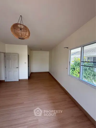 Spacious empty room with wooden flooring and large window