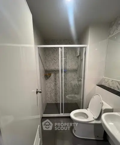 Modern bathroom with glass shower enclosure and sleek white fixtures.