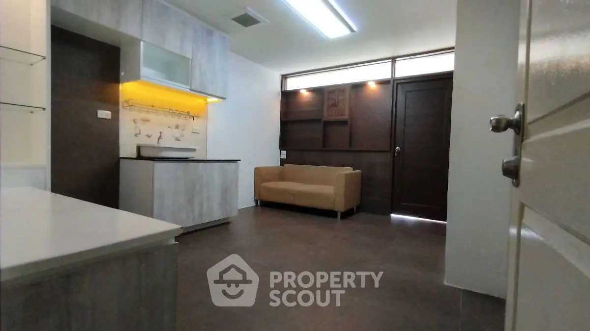 Modern living room with sleek kitchen and cozy sofa, perfect for urban living.