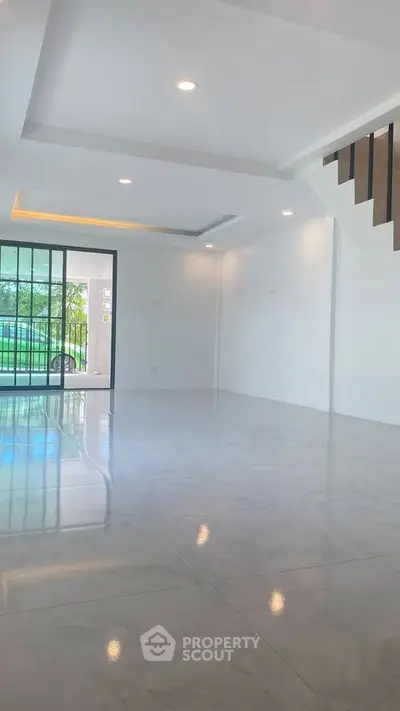 Spacious modern living room with large windows and sleek staircase
