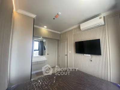 Modern bedroom with wall-mounted TV and air conditioning in stylish apartment.