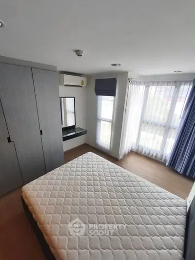 Modern bedroom with large windows and built-in wardrobe in a stylish apartment.