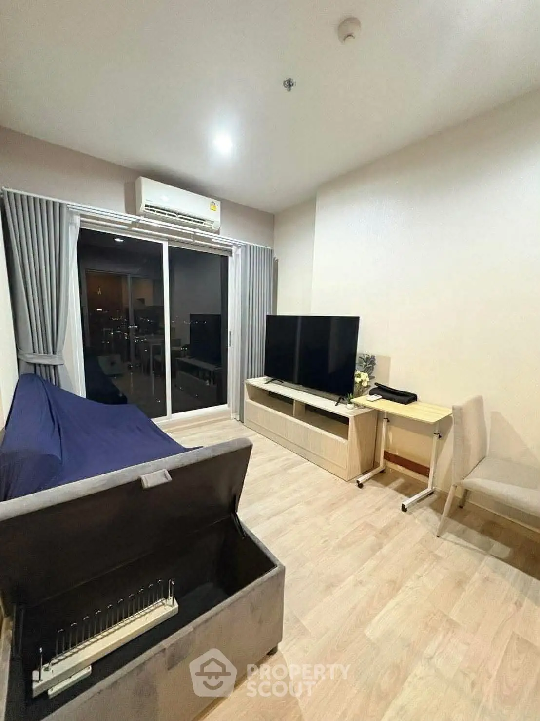 Modern living room with sleek furniture and large TV, featuring a cozy sofa and elegant flooring.