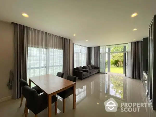 Spacious living room with gleaming tiled floors, modern furniture, and floor-to-ceiling windows offering a view of a serene garden.