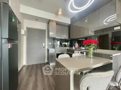 Modern kitchen with sleek cabinetry and dining area, featuring elegant lighting and a bouquet of red roses.
