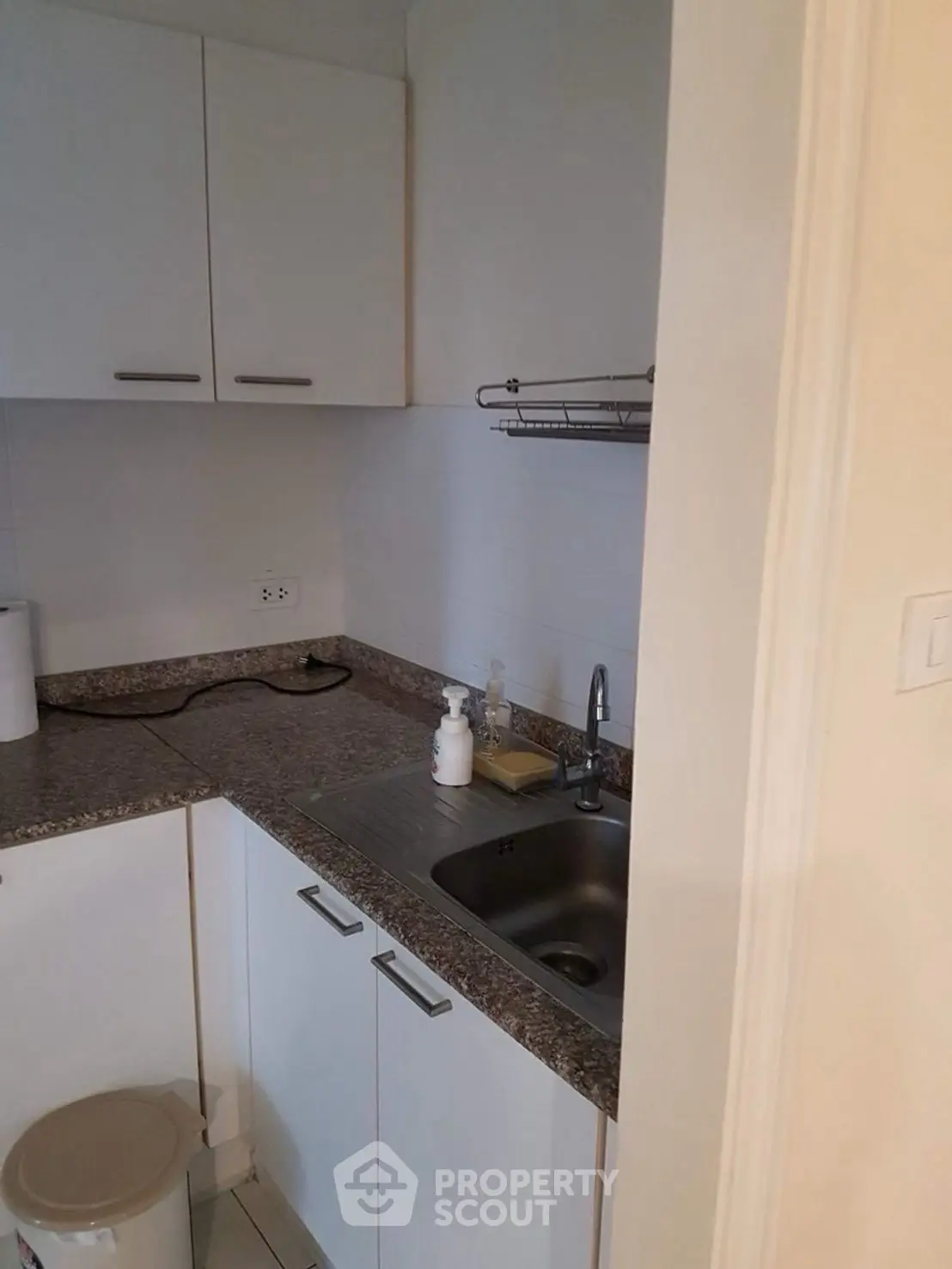 Compact kitchen with granite countertops and stainless steel sink in modern apartment.