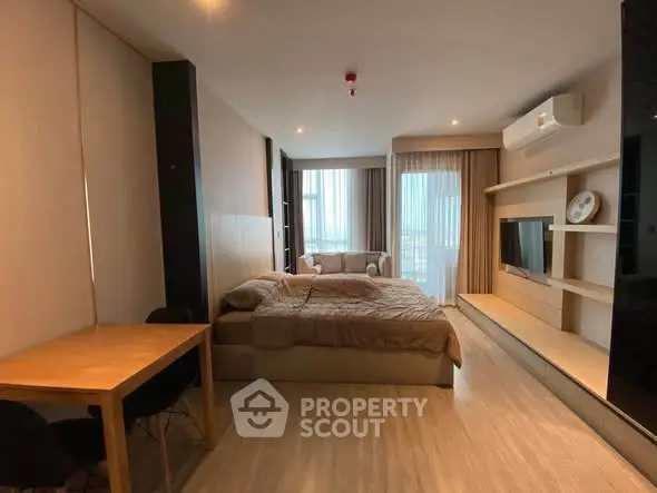 Modern studio apartment with cozy bed, stylish sofa, and sleek TV setup.
