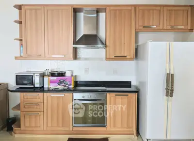 Modern kitchen with wooden cabinets, stainless steel oven, and large fridge